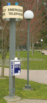 emergency callbox on a pole near some trees